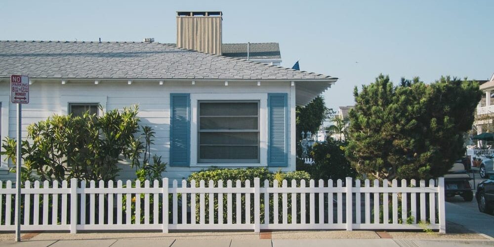 White fence in front of a white and blue house